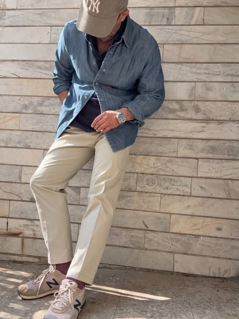 Denim overshirt, cream trousers, New Balance sneakers, and a New York cap