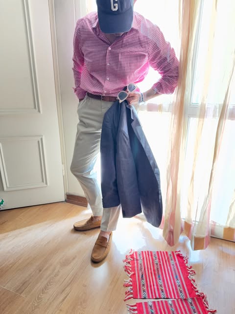 Gingham shirt, cream trousers, suede loafers, and a jacket held at the side