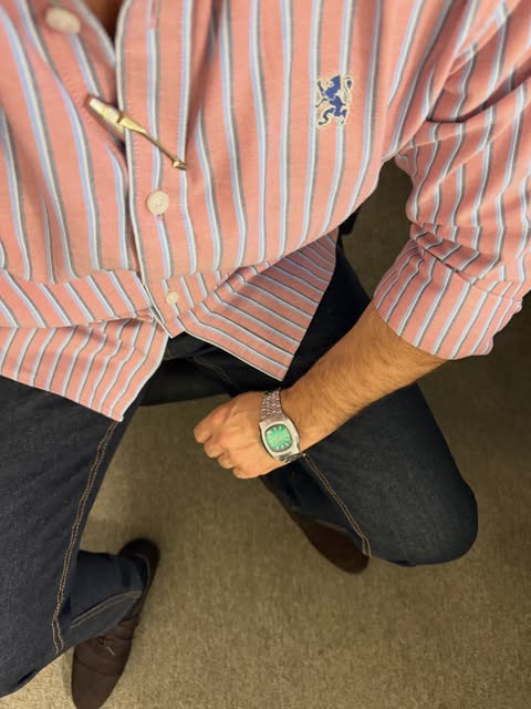 Striped oxford shirt, dark jeans, and a small watch with a green dial