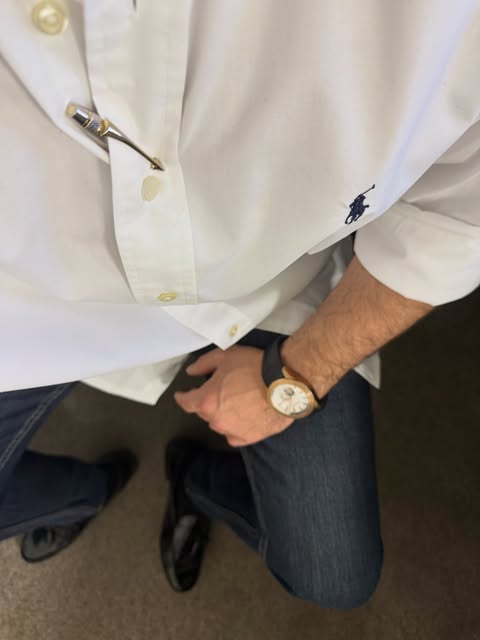 White oxford shirt, dark jeans, and a round gold-tone watch