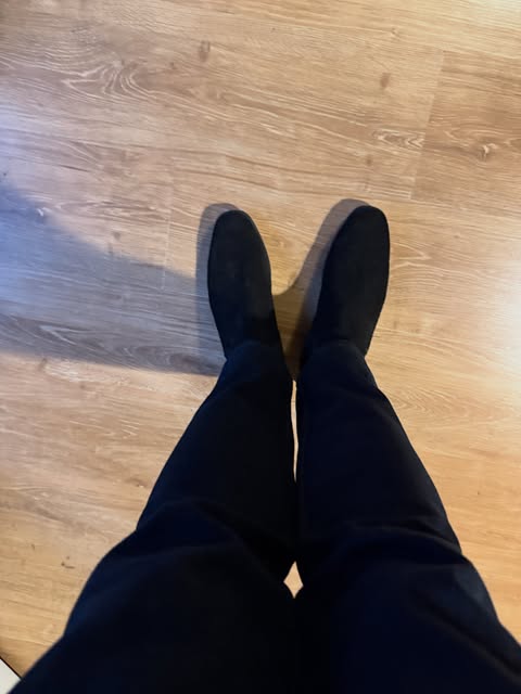Black suede boots worn with dark trousers, seen from above