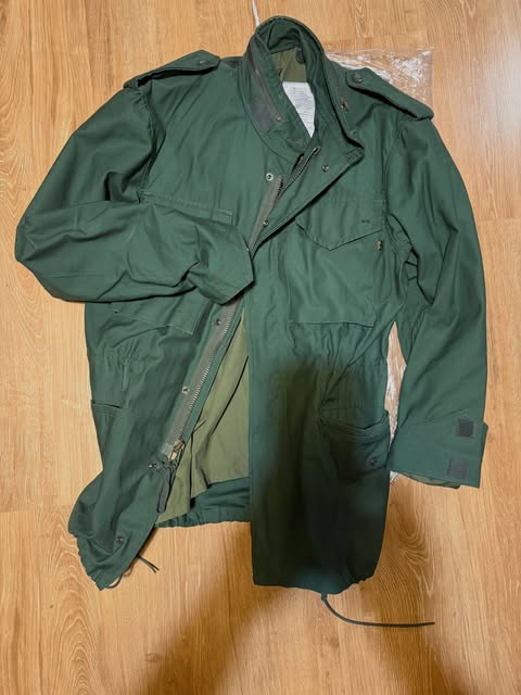 Olive field jacket laid open on a wood floor